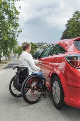 Behinderter Mensch mit Rollstuhl steigt in Auto ein